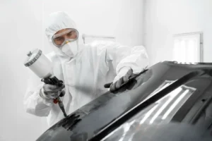 Técnico aplicando pintura automotriz con thinner para pintura en cabina profesional