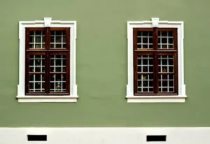 Fachada verde pintada con pintura para pared exterior y ventanas de madera con molduras blancas