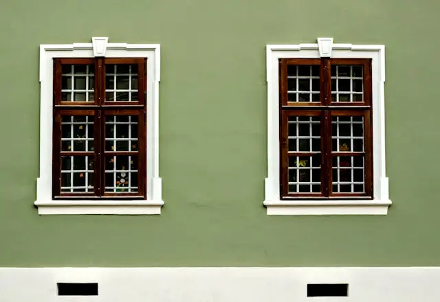 Fachada verde pintada con pintura para pared exterior y ventanas de madera con molduras blancas