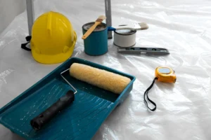 Herramientas de pintura y seguridad para proyectos de estilos arquitectónicos modernos, con rodillo, brochas, casco y pintura lista para aplicar