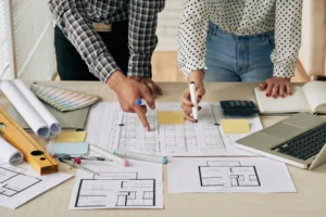 Persona mostrando planos de proyectos arquitectónicos de casas a otra persona